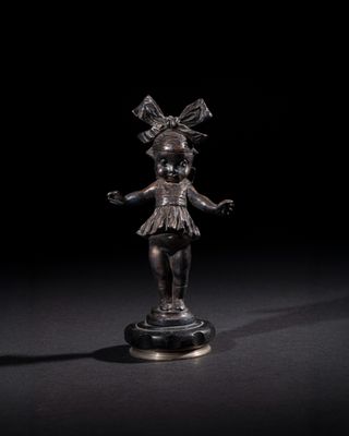 une statue en bronze représentant une jeune fille avec un nœud sur la tête et un nœud sur la tête