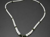un pendentif représentant un Bouddha en jade vert, orné de perles blanches et de perles de jade vert