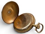 a gold pocket watch sitting on a white surface