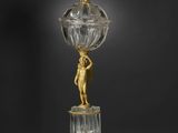 une figurine en or et en cristal représentant une femme tenant un globe terrestre