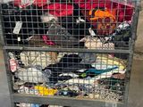 a metal cart filled with lots of clothes in a warehouse