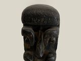 a black sculpture of a man ' s face on a white wall