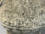 a stone vase that has a face on it