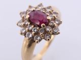 a close up of a gold ring with a ruby stone surrounded by white diamonds