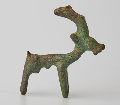 figurine en bronze représentant un cerf sur une surface blanche, avec un fond blanc