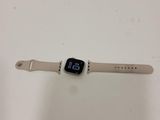 Une Apple Watch est posée sur une surface blanche, avec un bracelet autour.