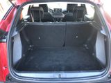 the back of a red car with its trunk open and seats folded down