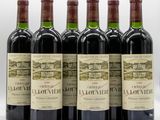 six bottles of red wine are lined up on a table