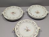 trois assiettes blanches ornées de motifs floraux sont posées sur une table