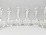 six vases en verre transparent sont alignés sur une surface blanche