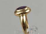 a close up of a gold ring with a purple stone on it