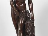 statue en bronze représentant une femme assise sur un rocher, les mains posées sur les genoux