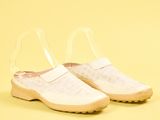 chaussures blanches à enfiler avec des lanières transparentes sur fond jaune
