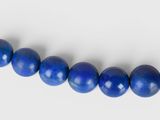 a strand of blue lapis beads on a white surface