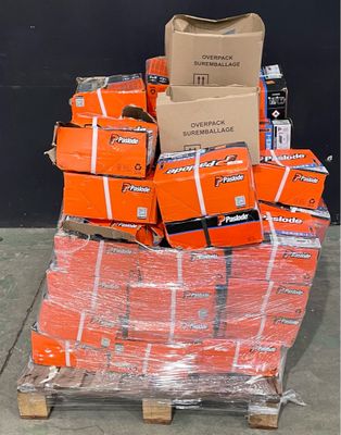 une pile de cartons orange posée sur une palette devant un mur noir