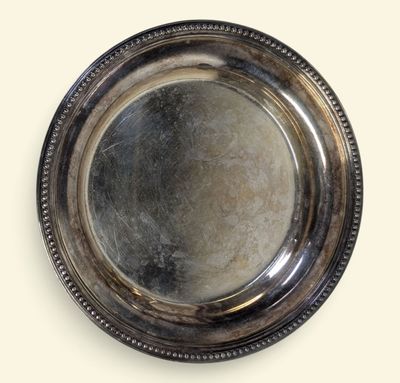 assiette en argent plaqué avec un bord festonné sur fond blanc