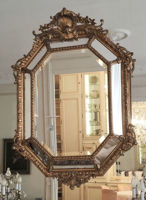 un miroir au milieu d'une pièce, avec un lustre en arrière-plan