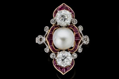 gros plan d'une bague en perles et diamants sur une surface noire