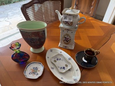 a wooden table with a vase, plate, and cups on it