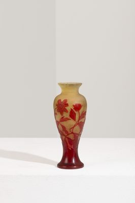 un vase rouge posé sur une surface blanche, avec un fond blanc