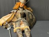 a doll that is sitting on a couch with a sword