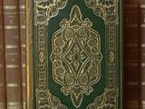 un vieux livre posé sur une étagère en bois, à côté d'une pile de livres
