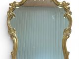 an image of a gold framed mirror hanging on a wall