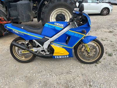 a blue and yellow motorcycle parked next to a truck