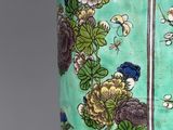 a green vase with flowers and birds painted on it