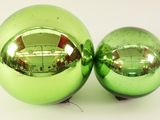 two shiny green christmas balls on a white surface