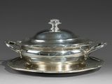 un service ancien en argent avec un couvercle et une soucoupe posée sur une autre soucoupe