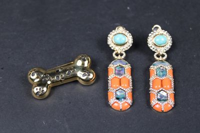 deux paires de boucles d'oreilles et un os pour chien posés sur une surface noire