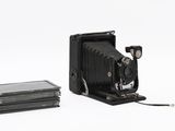 a black camera and a stack of books on a white surface