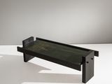 une table basse noire avec un plateau en verre posé sur un piètement blanc