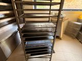 une cuisine équipée d'une cuisinière, d'un four et d'une étagère sur laquelle sont posées des plaques de cuisson