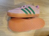 pink and green adidas sneakers on a wooden floor