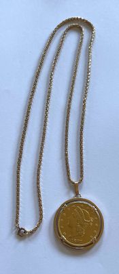 un collier orné d'une pièce de monnaie, posé sur une surface blanche