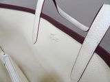 a white purse with a red handle on a table