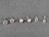 quatre paires de boucles d'oreilles en diamant posées sur une surface grise