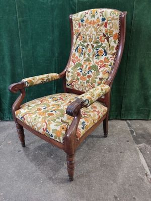 an old chair with a floral upholstered seat and arms