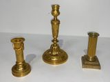 trois bougeoirs dorés posés sur une table blanche