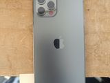 Un iPhone est posé sur une table en bois, à côté d'un jean bleu.