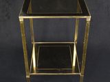 une table d'appoint noire et dorée avec un plateau en verre