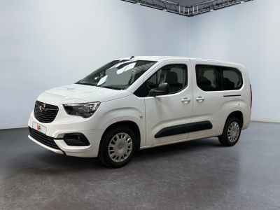 La camionnette blanche est garée dans une grande pièce au sol gris.