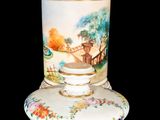 a white vase with a painting on it sitting on a table