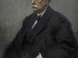 portrait d'un homme en costume-cravate, assis sur une chaise