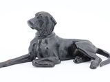 statue of a black dog laying down on a white surface