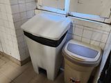 a toilet and a trash can in a small bathroom