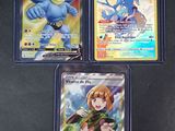Trois cartes Pokémon différentes sont posées sur une surface noire