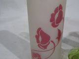 un verre orné d'une fleur rose à côté d'un morceau de brocoli